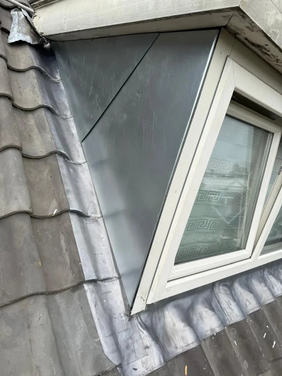 Metal dormer roofs, cheeks and long gutters alongside tiled surfaces.