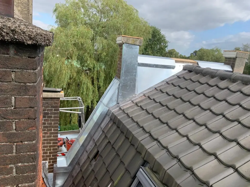 A photographic study of tiles, masonry and metal flashing around chimneys.